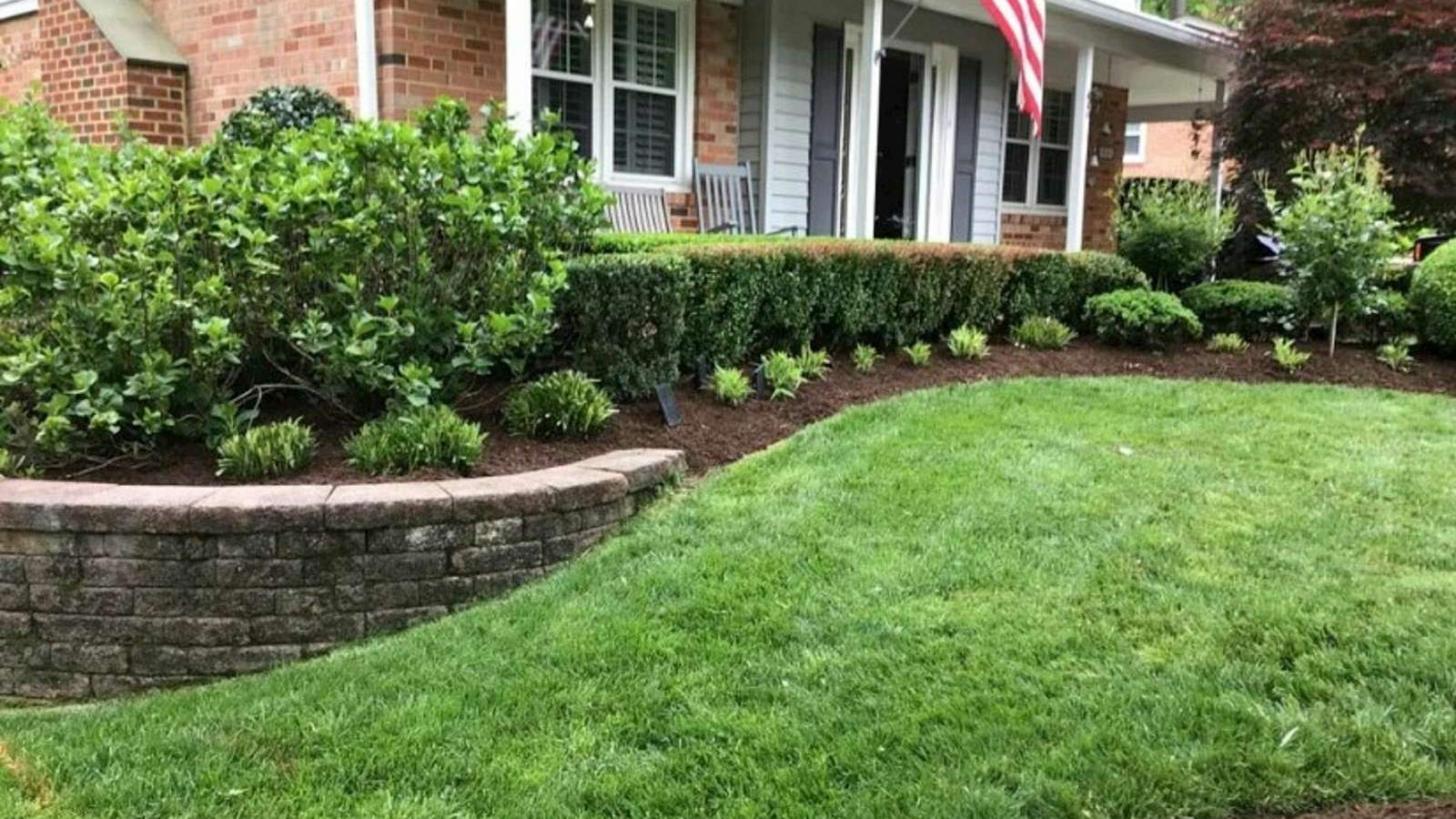 Freshly mulched garden bed along a landscaped home's retaining wall